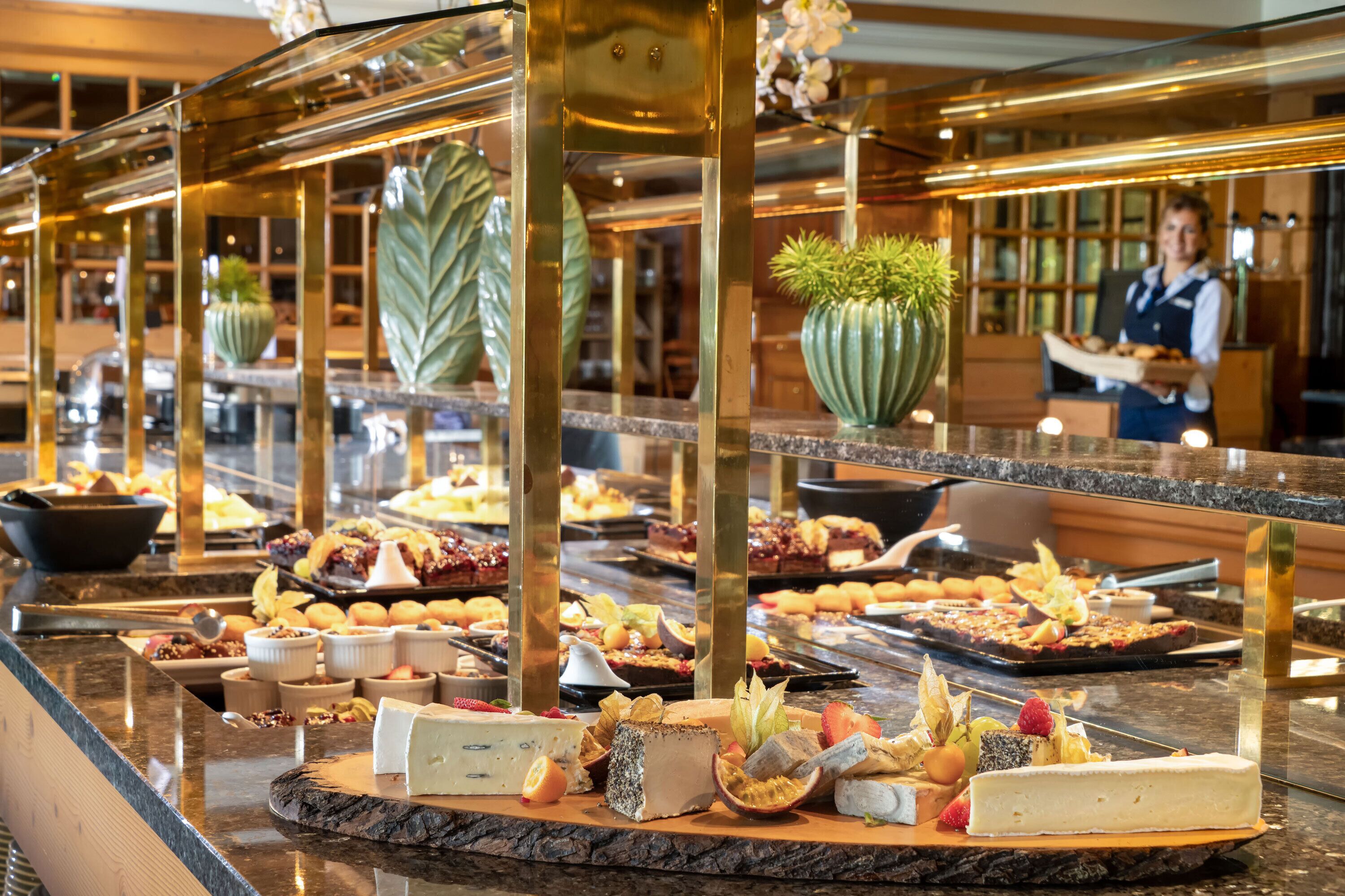 A buffet with various cheeses, fruits, and pastries.