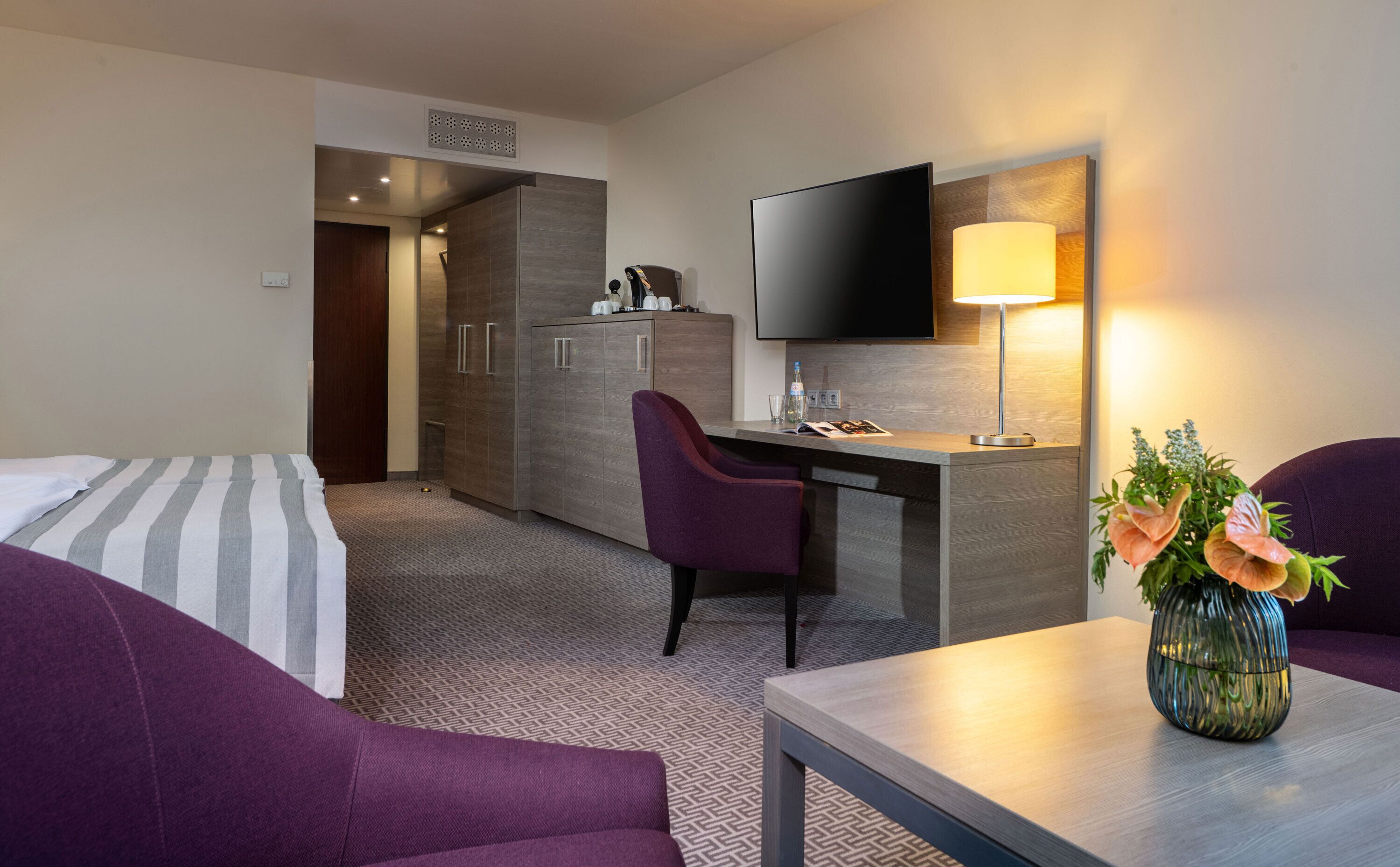 Ein Hotelzimmer mit einem Bett, einem Schreibtisch, einem Stuhl, einem Fernseher und einer Lampe.