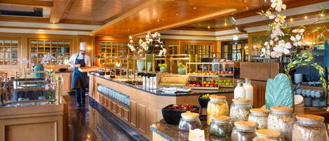 A buffet area with a variety of food items and a chef preparing food.