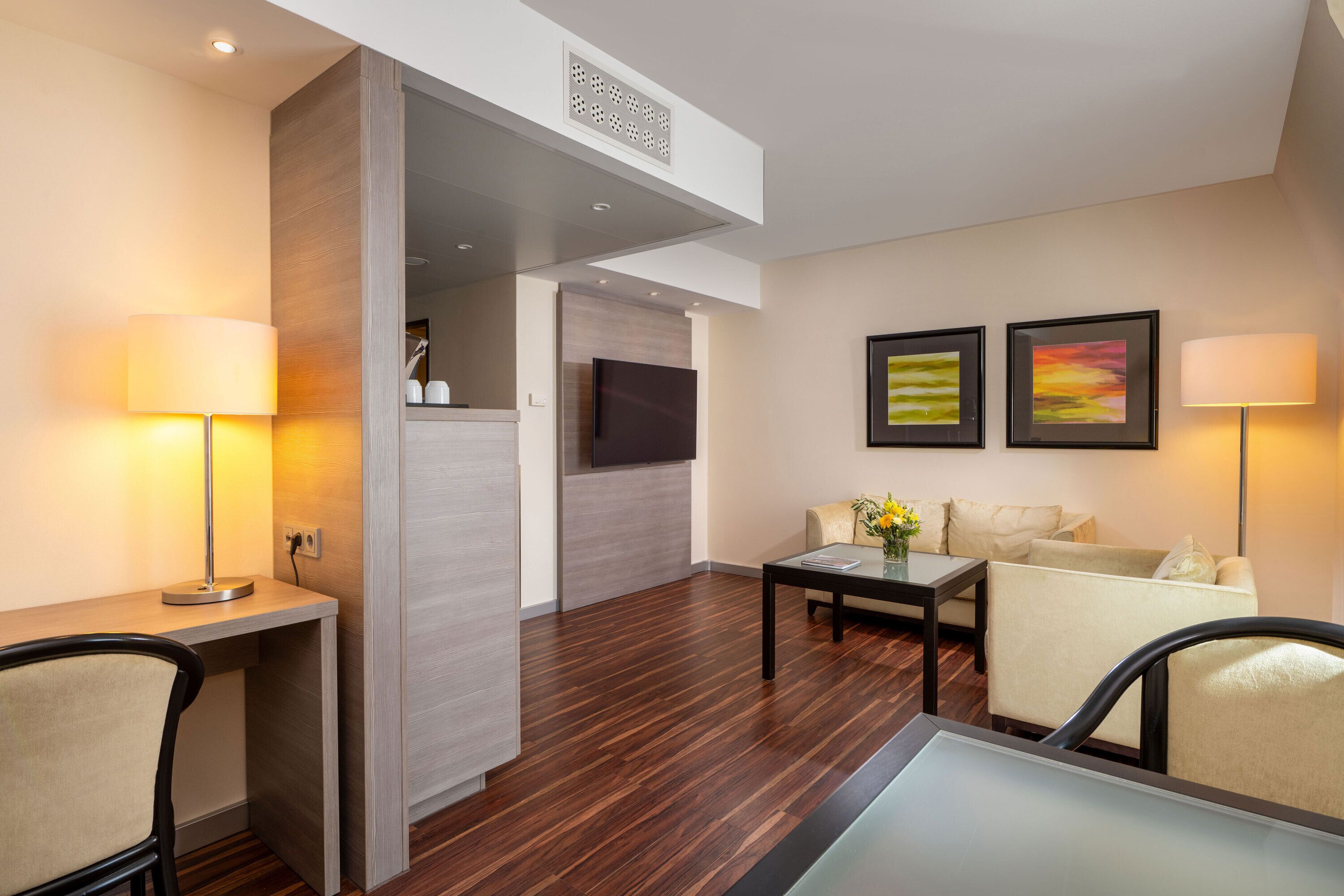 A modern living room with a sofa, two armchairs, a coffee table, and a TV mounted on the wall.