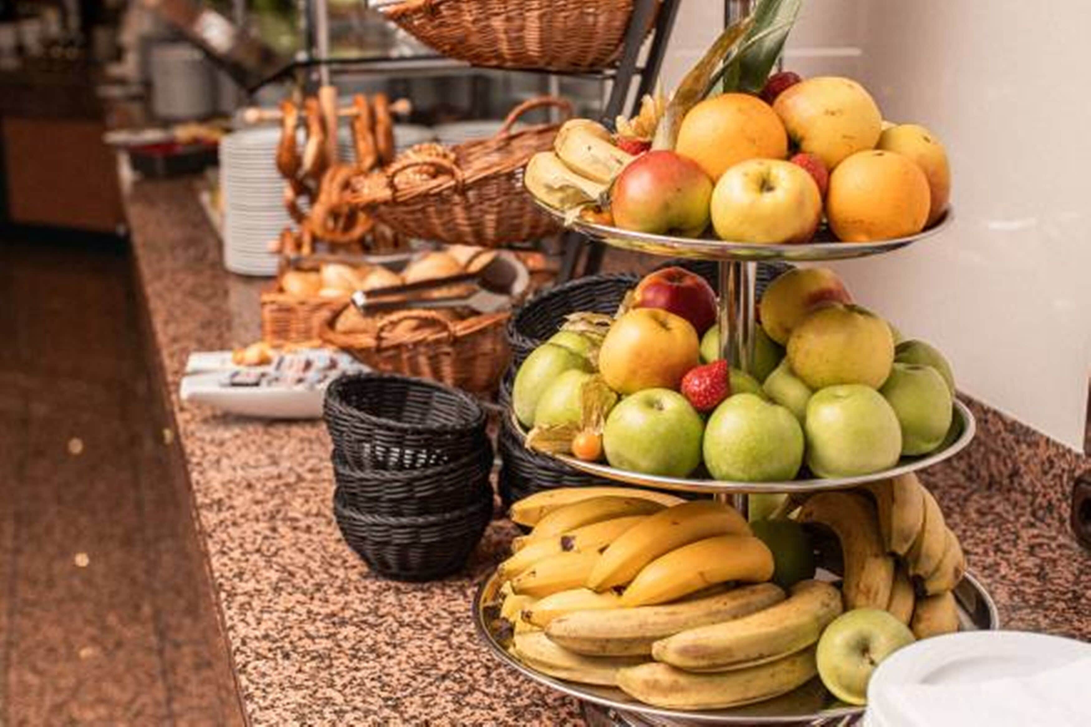 Una mesa de buffet con diversas frutas y cestas de pan.