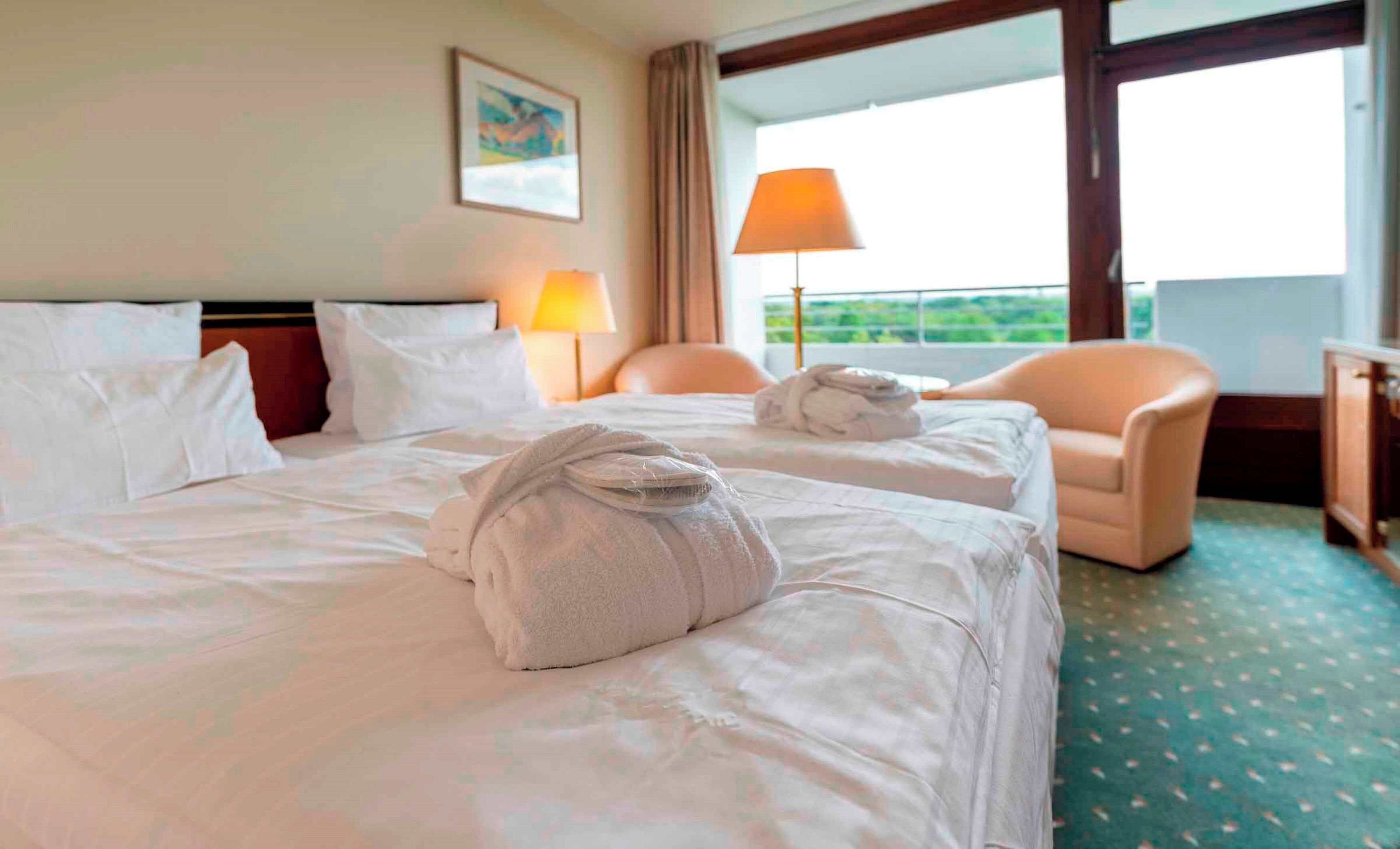 Une chambre d’hôtel avec deux lits, une chaise, une lampe et une vue sur l’extérieur.