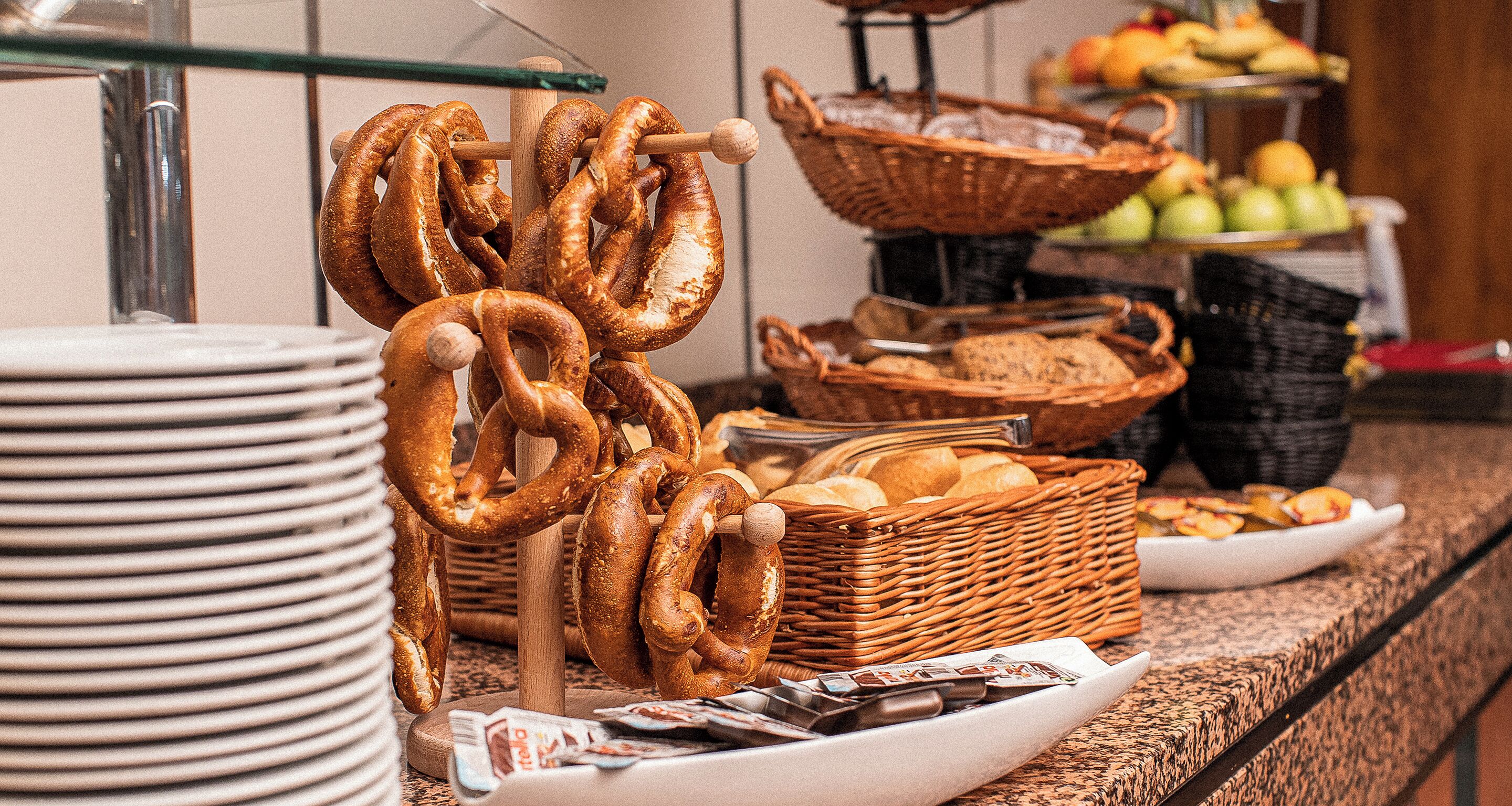 A buffet with pretzels, bread, and various baked goods.