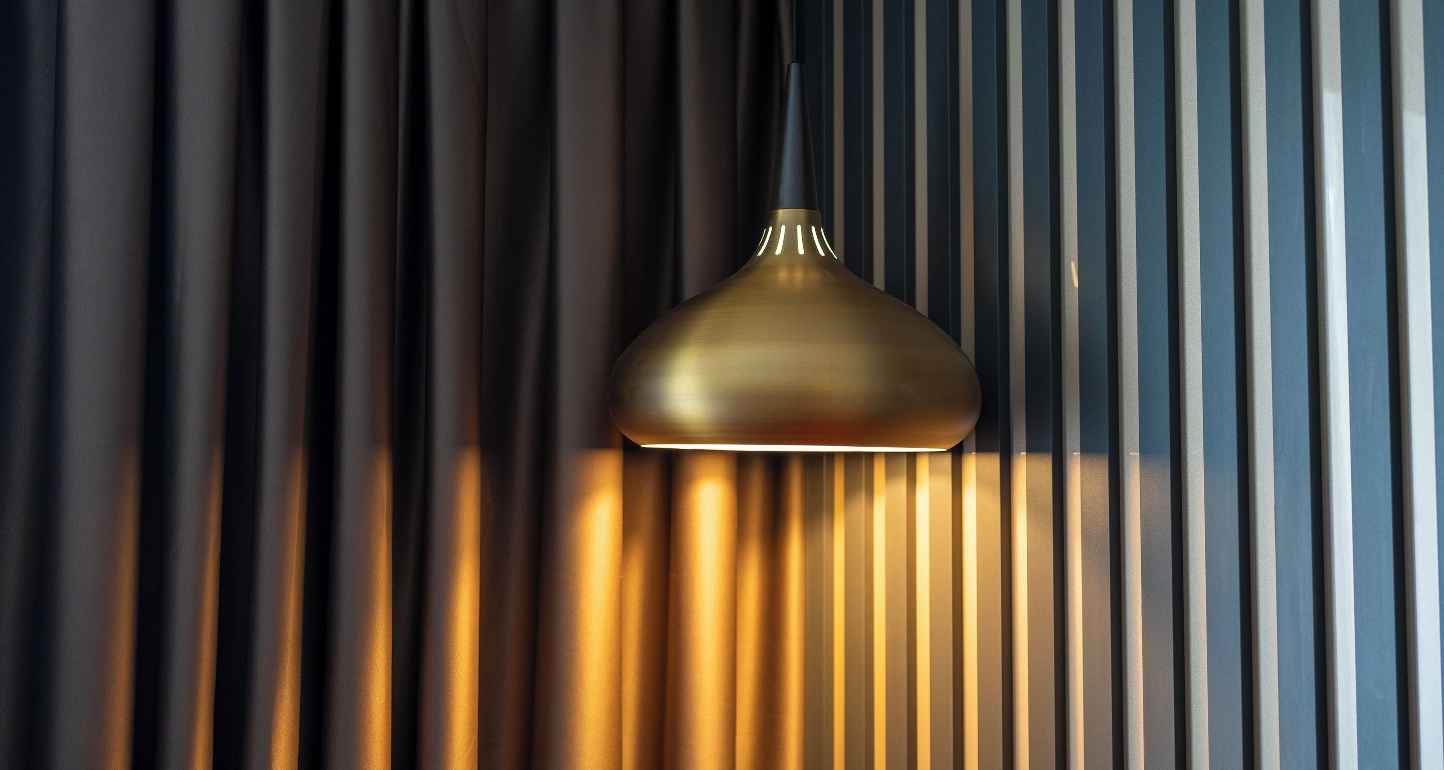 Un luminaire suspendu, de type suspension, avec un fini métallique, fixé au plafond.