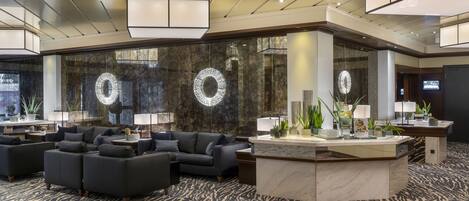 A modern lobby with a reception desk, sofas, and a patterned carpet.
