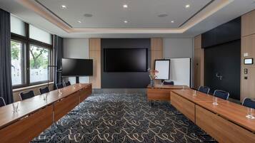 A conference room with a large table, chairs, a TV, and a whiteboard.