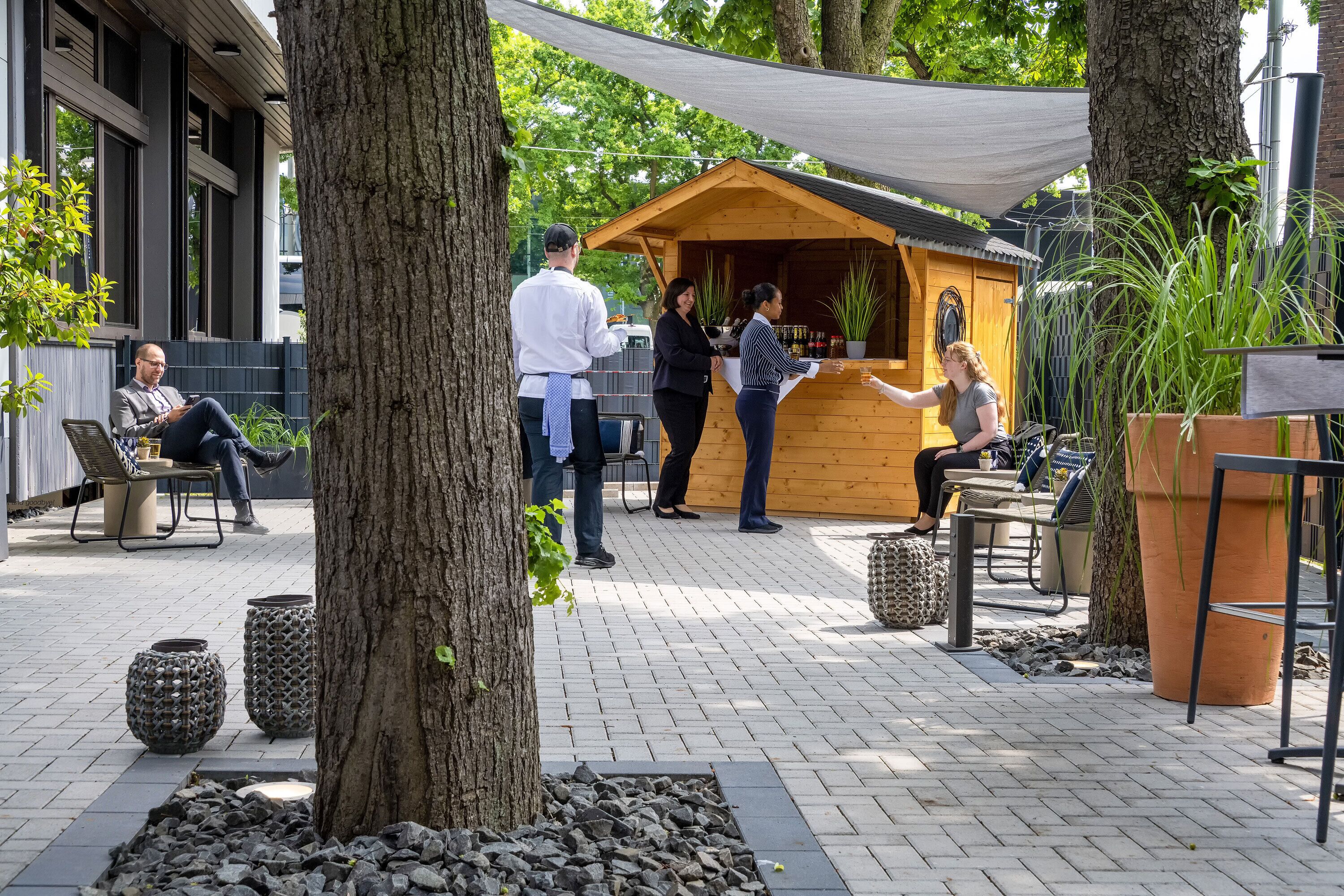 An outdoor patio area with seating, a wooden structure, and a shaded area.