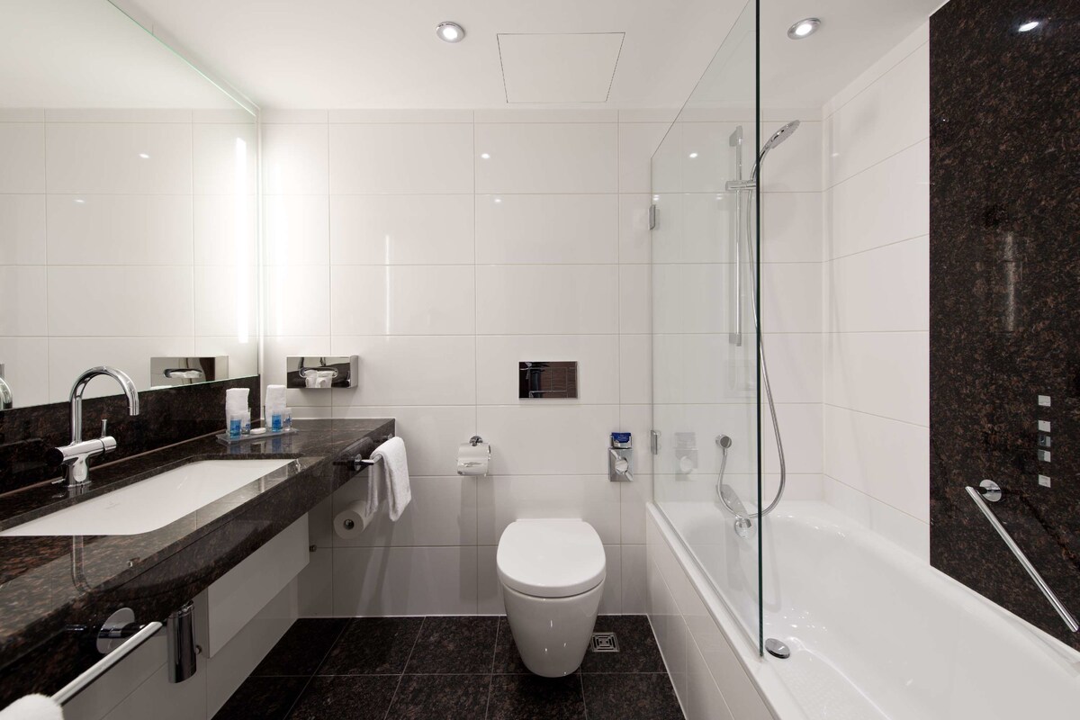 Un baño moderno con lavamanos, inodoro y ducha.