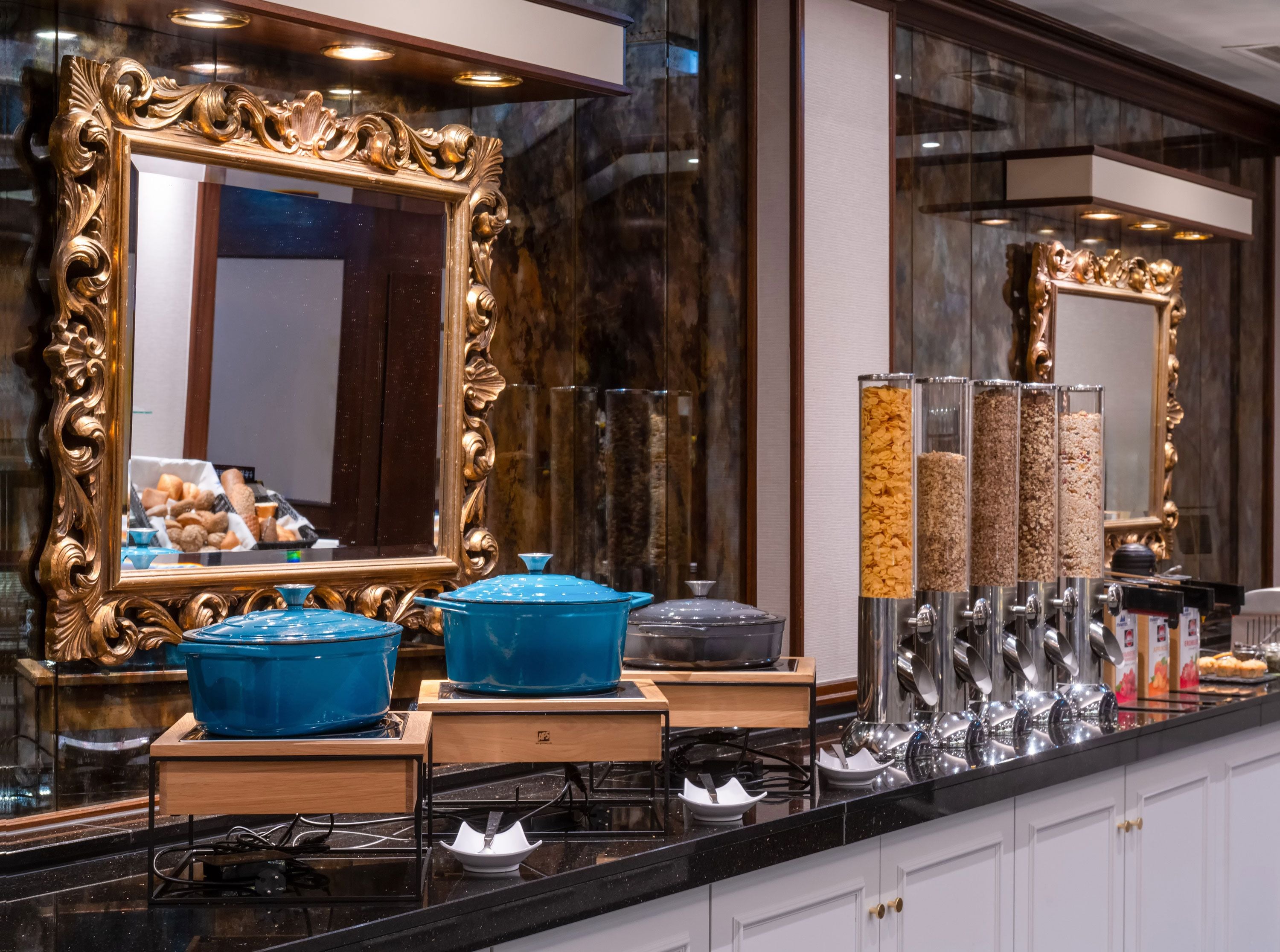 A kitchen with a large ornate mirror, blue serving bowls, and a coffee machine.