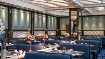 A dining area with blue upholstered booths, tables set with white tableware, and decorative lamps.