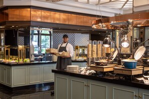 Un chef dans une cuisine moderne, avec un buffet proposant un comptoir rempli de plats et une variété d'ustensiles de cuisine.