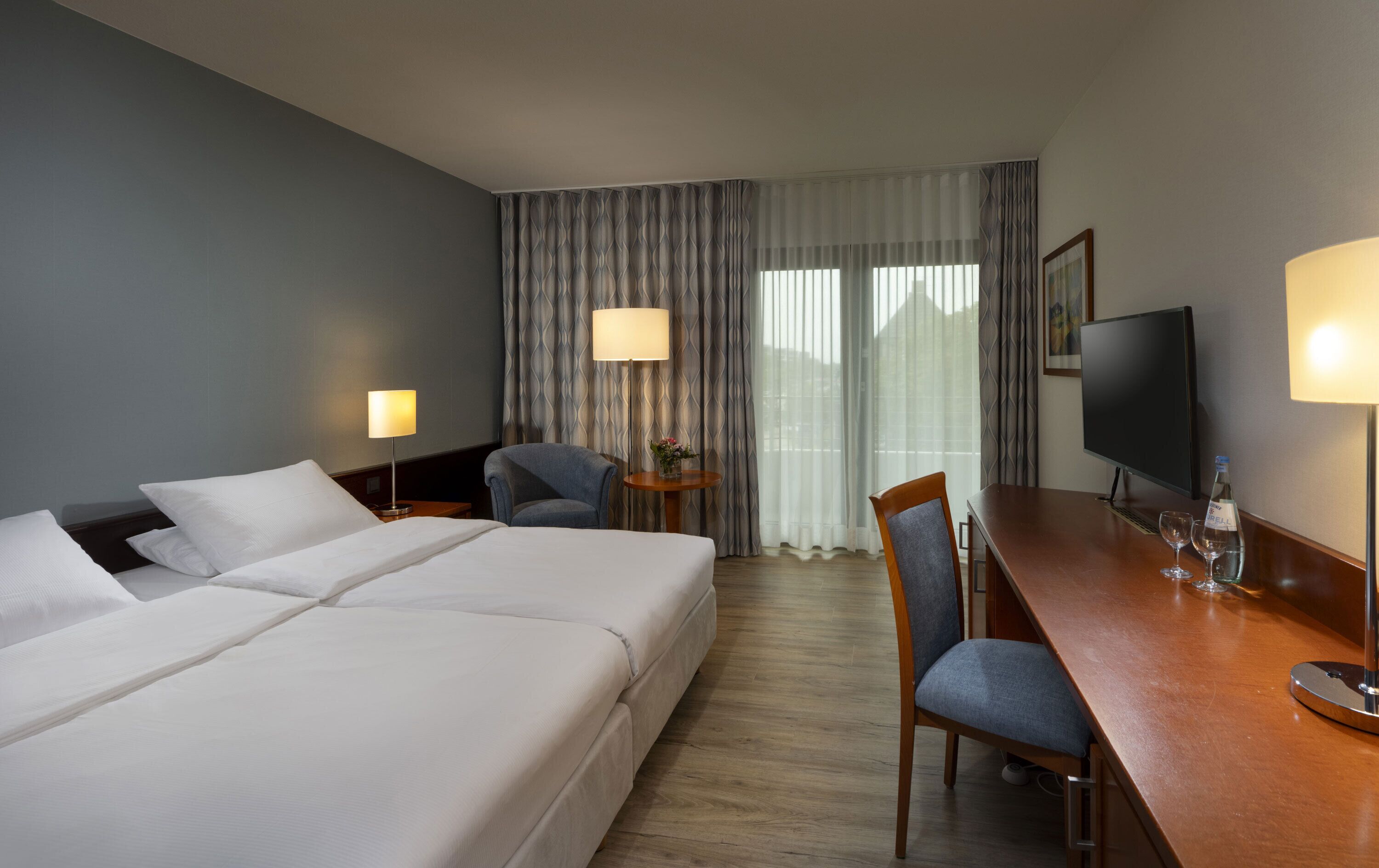 Een hotelkamer met twee bedden, een bureau met een televisie en een stoel.