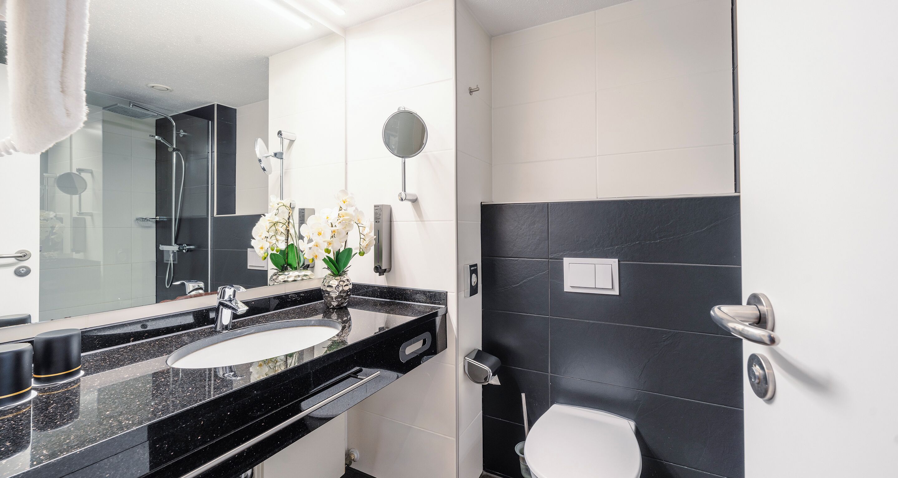 Uma casa de banho moderna com lavatório de bancada preta, espelho e sanita.