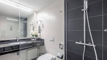 Un baño moderno con dos lavamanos, un espejo grande, una ducha y un inodoro.