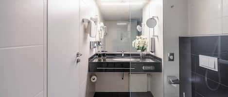 A modern bathroom with a black countertop sink, a glass shower enclosure, and a white toilet.