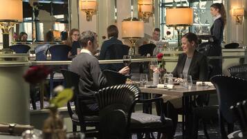 Ein Restaurant mit gedeckten Tischen, einem Kellner, der sich um Gäste kümmert, und einer Bar.