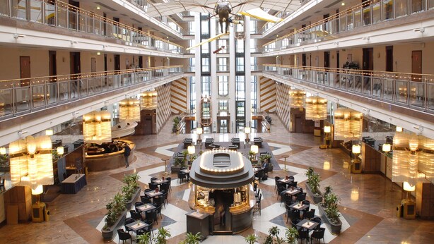 Un amplio vestíbulo de hotel con varios pisos, una zona de estar central y una exhibición náutica.