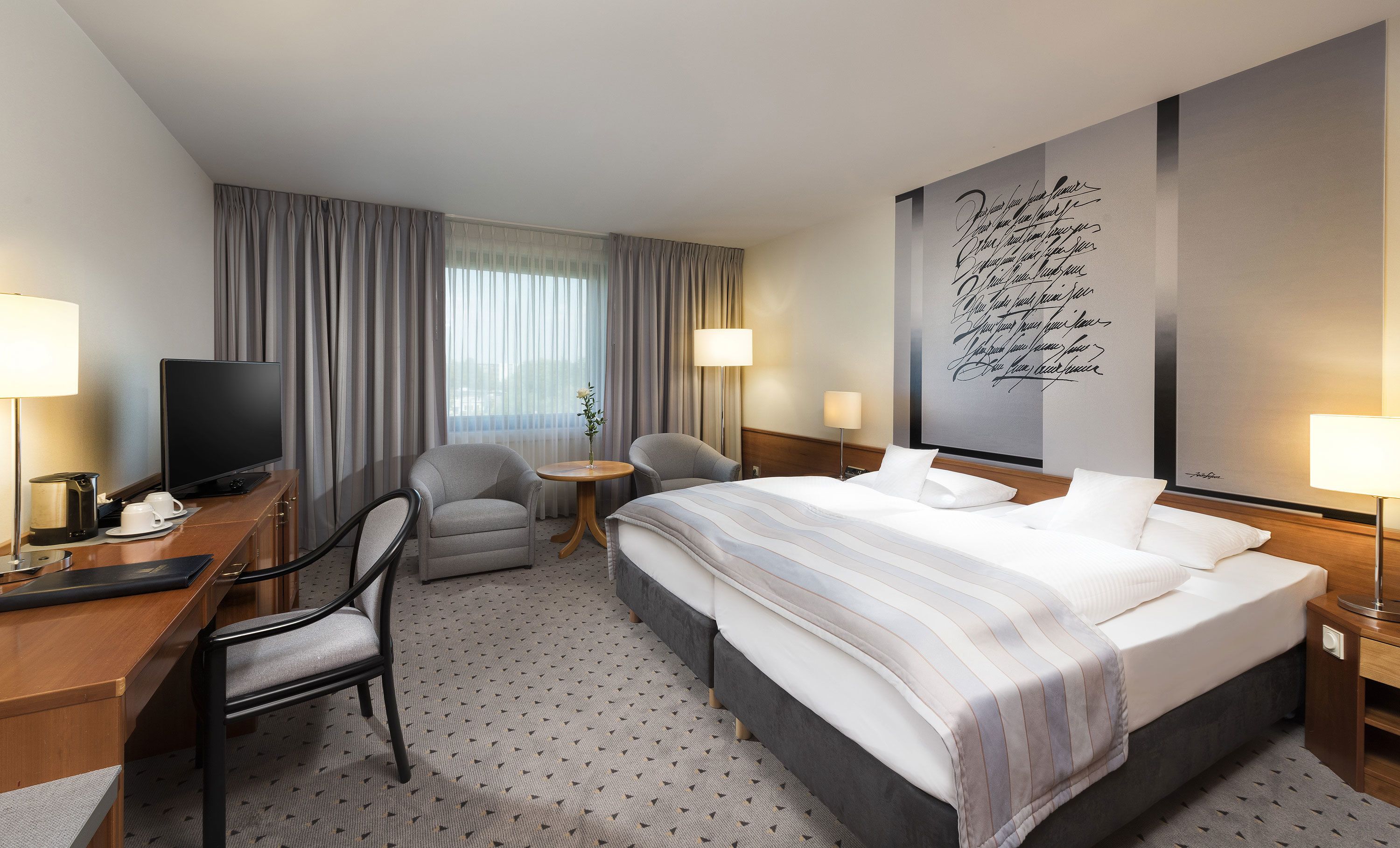 A hotel room with a bed, a desk, a television, and a chair.