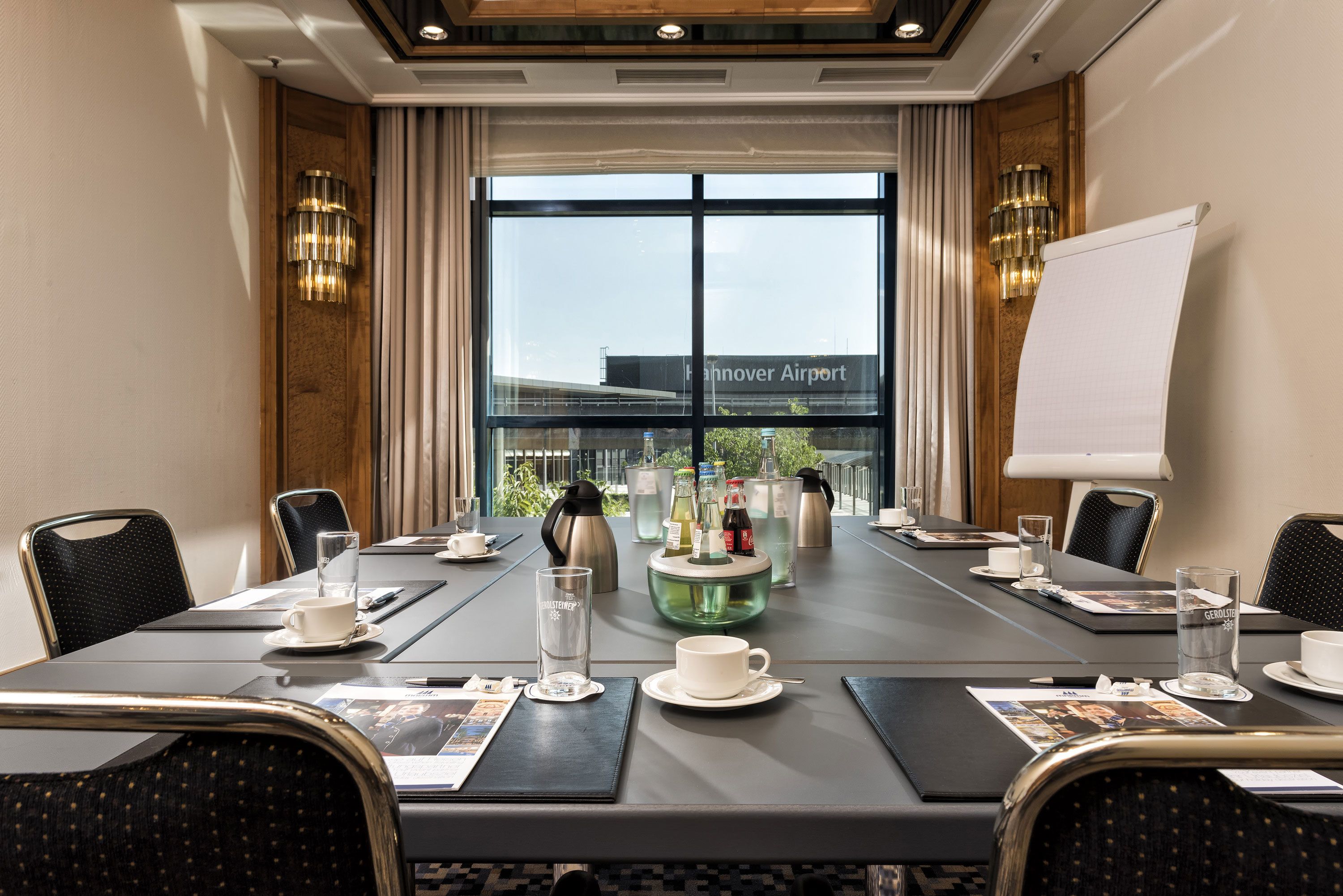 A conference room with a large table, chairs, a whiteboard, and a view of the airport.