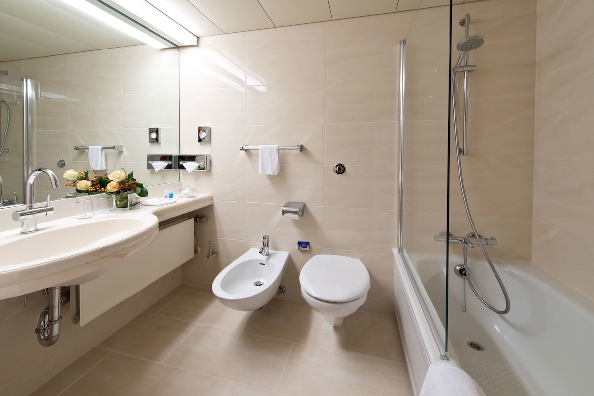 Un baño moderno con lavamanos, bidé, inodoro y ducha.