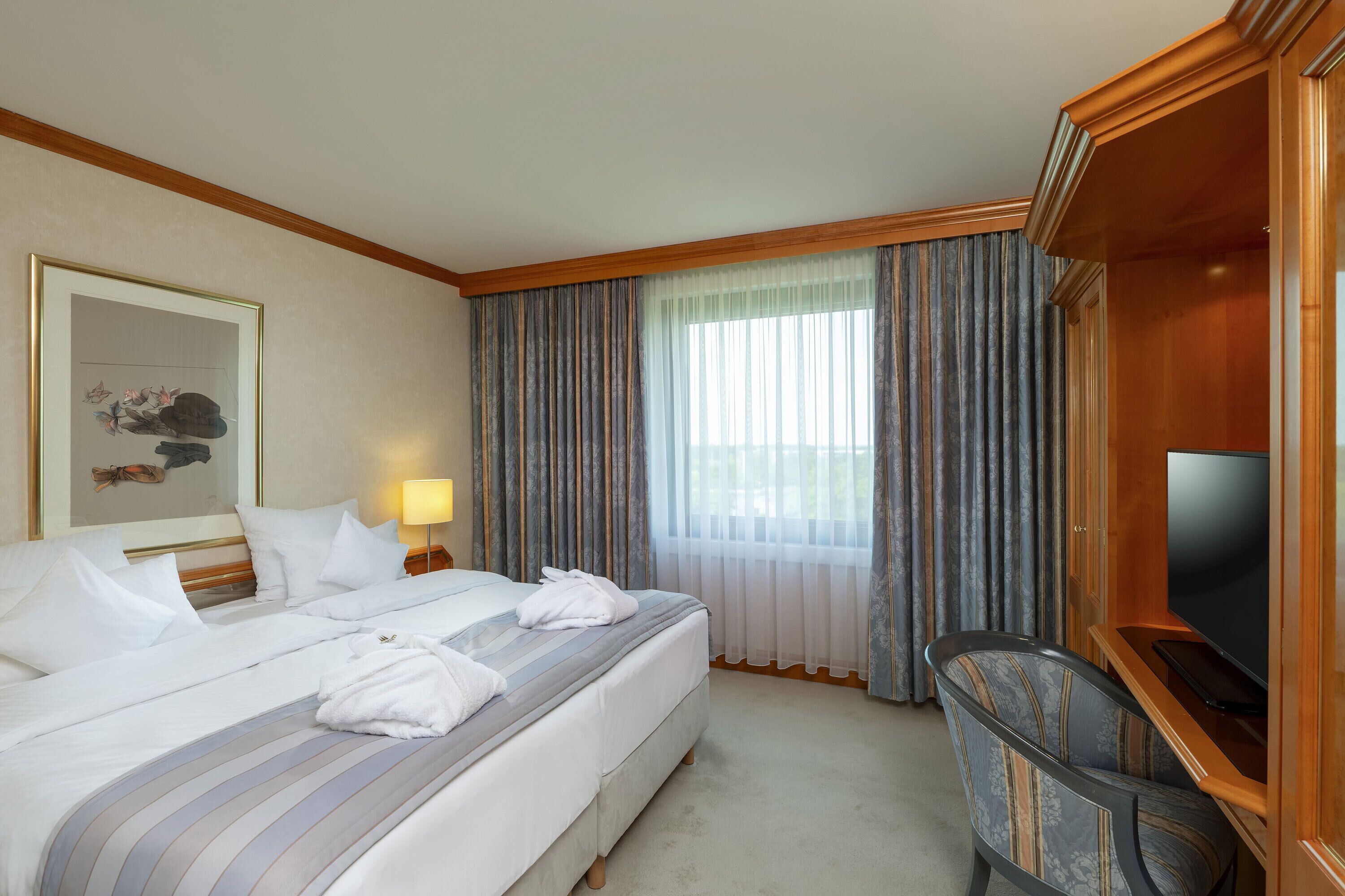 Una habitació d'hotel amb un llit gran, una televisió, un escriptori i una cadira.