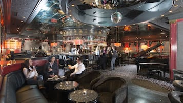 A bar area with seating, a piano, and a circular ceiling design.