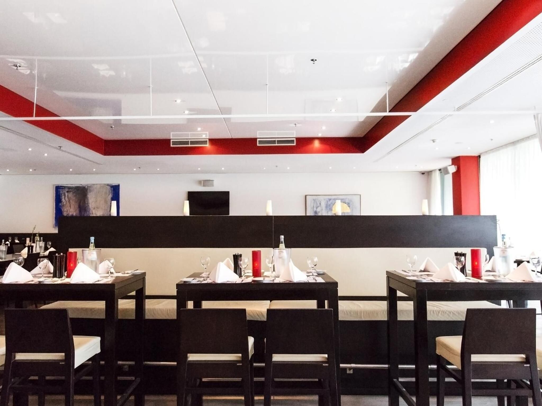 Ein modernes Restaurant mit gedeckten Tischen, einer schwarzen Theke und Kunstwerken an den Wänden.