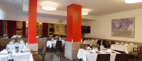 A restaurant with multiple tables set for dining, a bar area, and a television mounted on the wall.