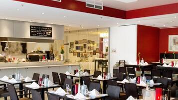 A restaurant with multiple tables set for dining, a bar area, and a visible menu board.