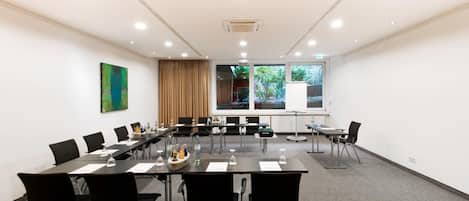 A conference room with a long table, black chairs, and a whiteboard.