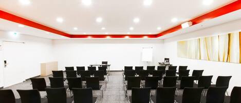 A conference room with rows of black chairs, a whiteboard, and a projector.