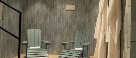 A spa area with two Adirondack chairs, a tiled wall, and a sign indicating a spa experience.