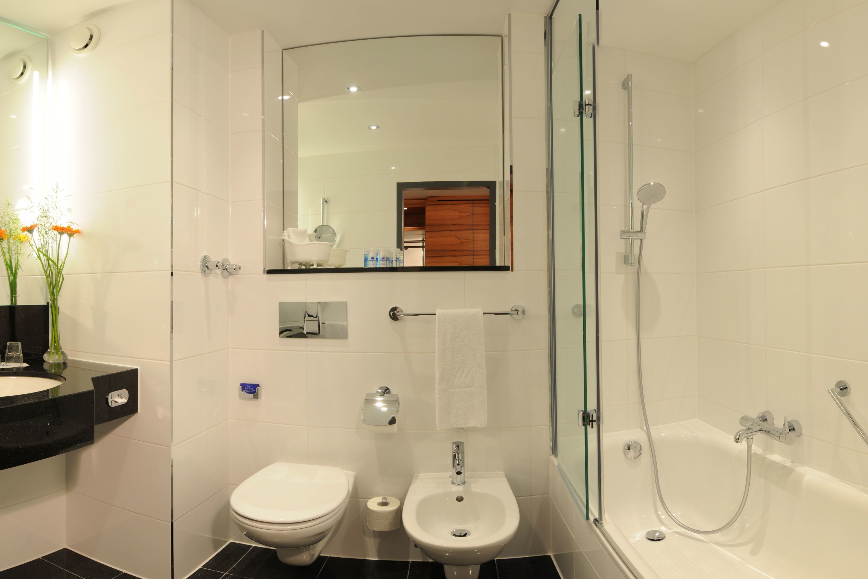 A modern bathroom with a toilet, bidet, sink, and bathtub.