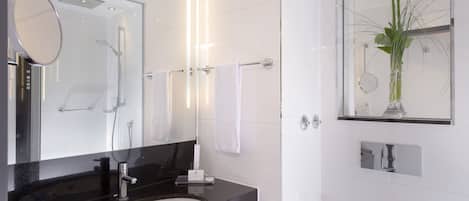 A modern bathroom with a black countertop, white sink, and a large mirror.
