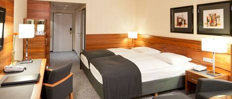 A hotel room with a large bed, two bedside tables, a desk with a chair, and a mirror.