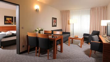 Une chambre d’hôtel comprenant un lit, un canapé, une table à manger avec des chaises, un bureau avec une chaise et un téléviseur.