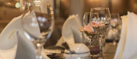 A dining table set with white napkins, a glass, a small bowl, and a glass of water.