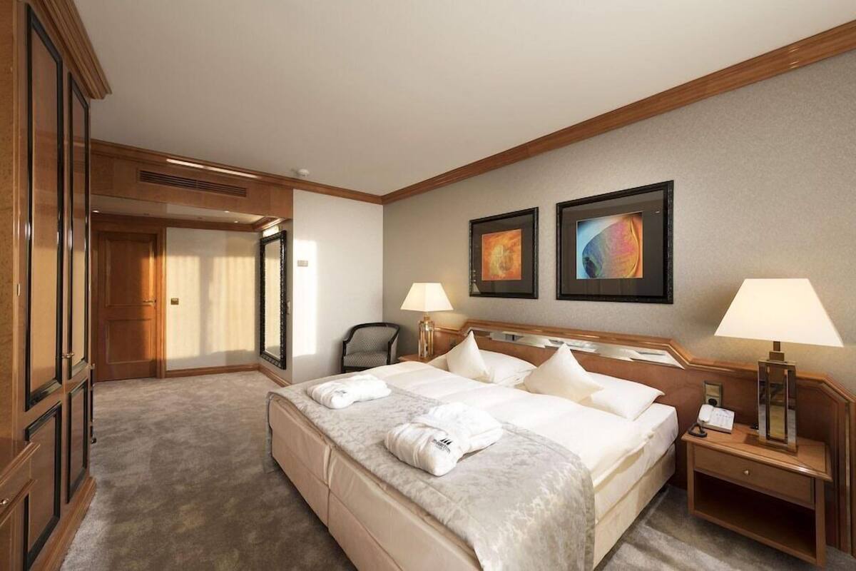 A hotel room with a large bed, two bedside lamps, a desk, and a chair.