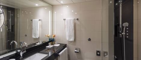 A modern bathroom with a dual sink vanity, a large mirror, a toilet, and a walk-in shower.