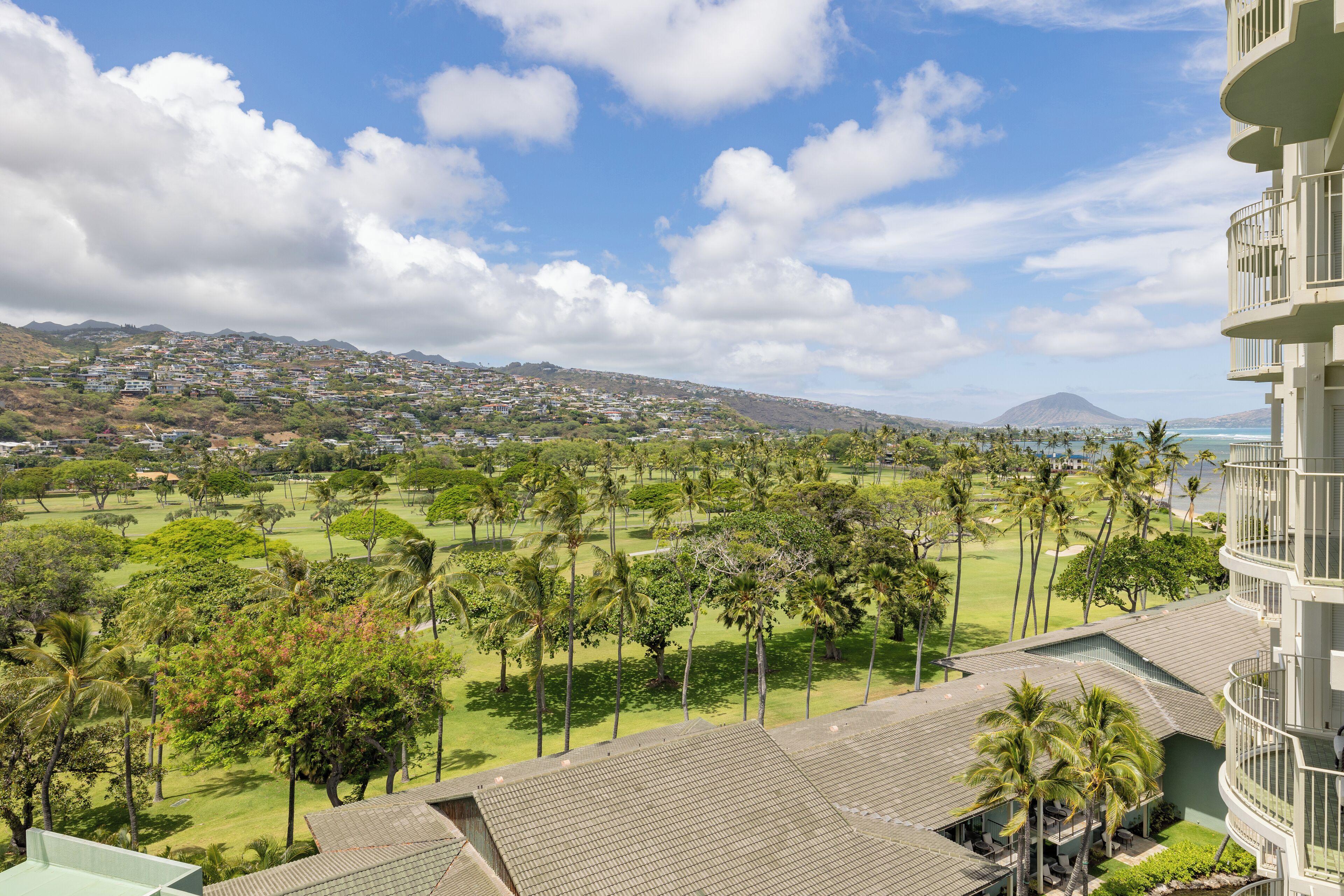 A high-rise hotel with a view of a golf course and a mountain in the distance.