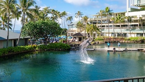 A resort pool with palm trees, a water fountain, and a view of the ocean. - The Kahala Hotel & Resort (Honolulu)
