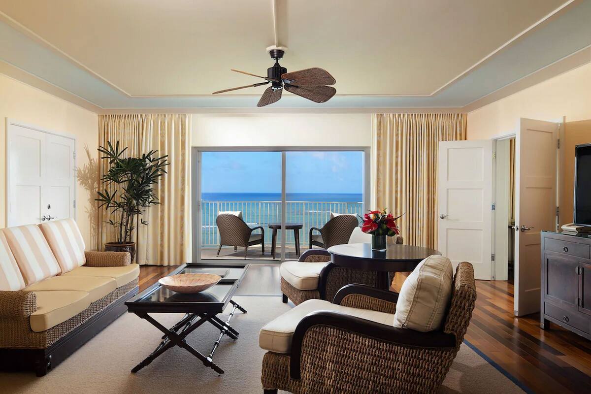 A spacious living room with a balcony, a sofa, a coffee table, and wicker furniture.