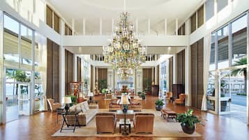 A spacious lobby with a large chandelier, multiple seating areas, and large windows offering views.