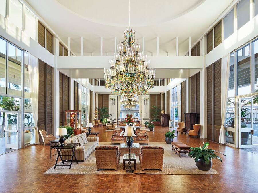 A spacious lobby with a large chandelier, multiple seating areas, and large windows offering views.