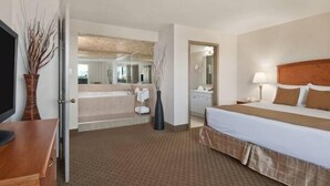 Een hotelkamer met een bed, nachtkastje, lamp en een badkamer die door een open deur zichtbaar is.