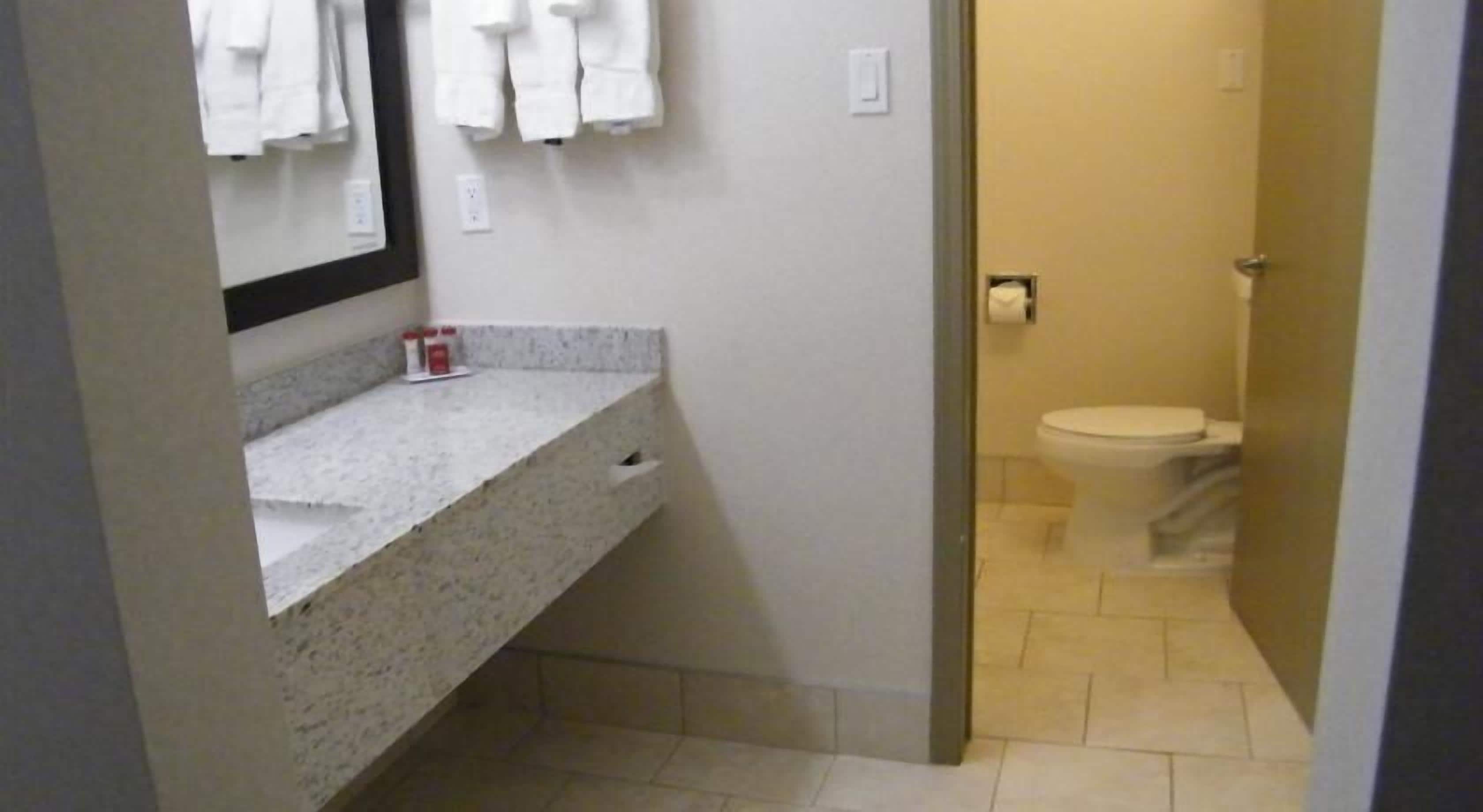 Un baño con lavamanos, espejo e inodoro blancos.