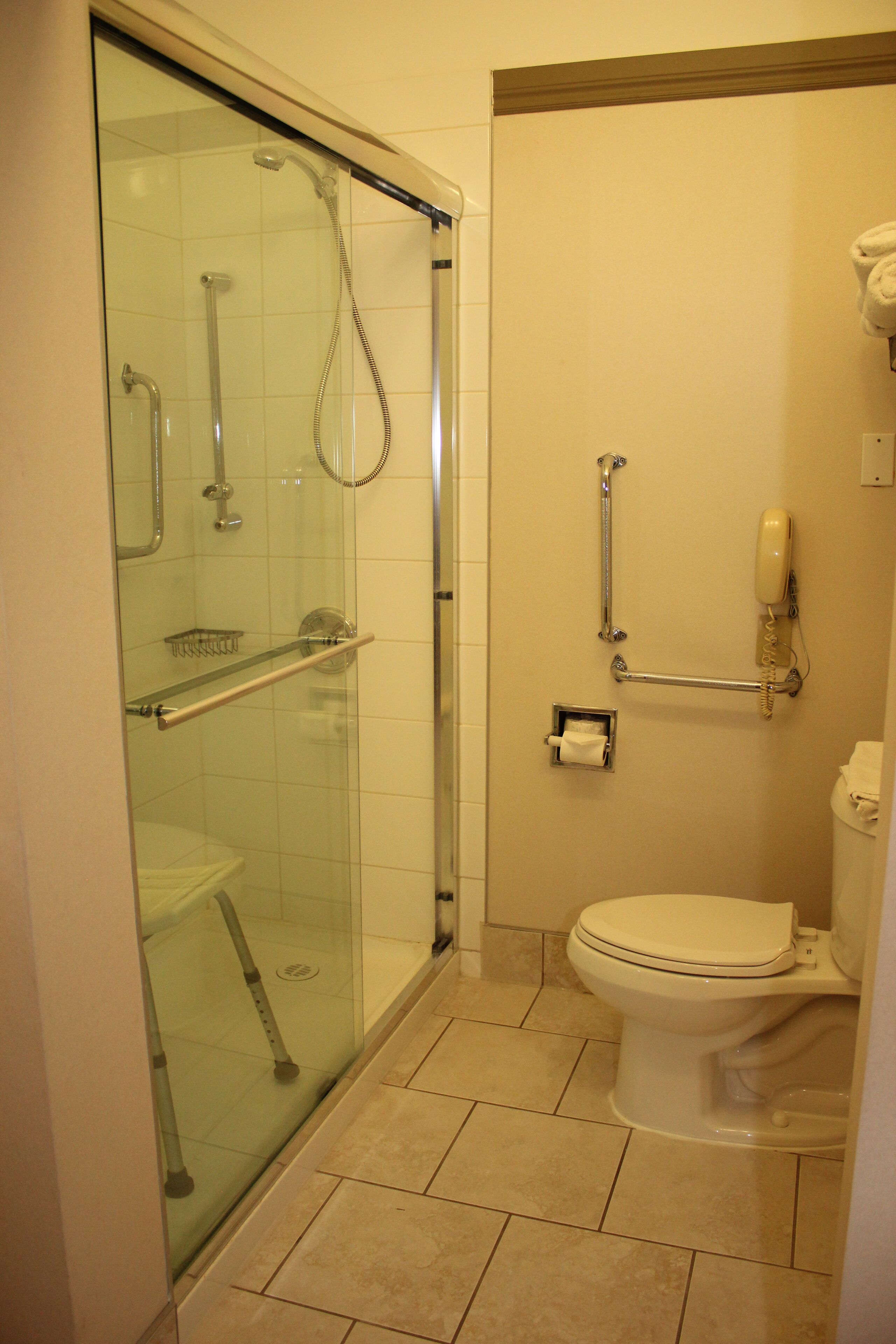 A bathroom with a glass-enclosed shower, a toilet, and a hand dryer.