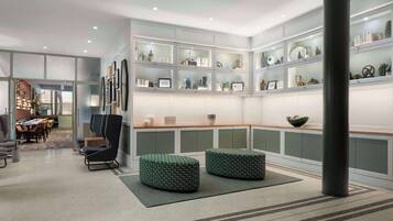 Um interior moderno com área de estar, exposição de objetos decorativos e vista para outro cômodo.