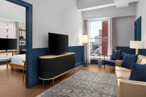 Relax in a stylish room with a large flat-screen TV, comfortable sofa, and a bed with a wooden frame, offering a city view.