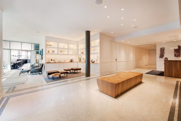 A spacious lobby with a reception desk, seating area, and a large wooden bench. - Hotel Theo New Orleans, Tapestry Collection by Hilton (New Orleans)